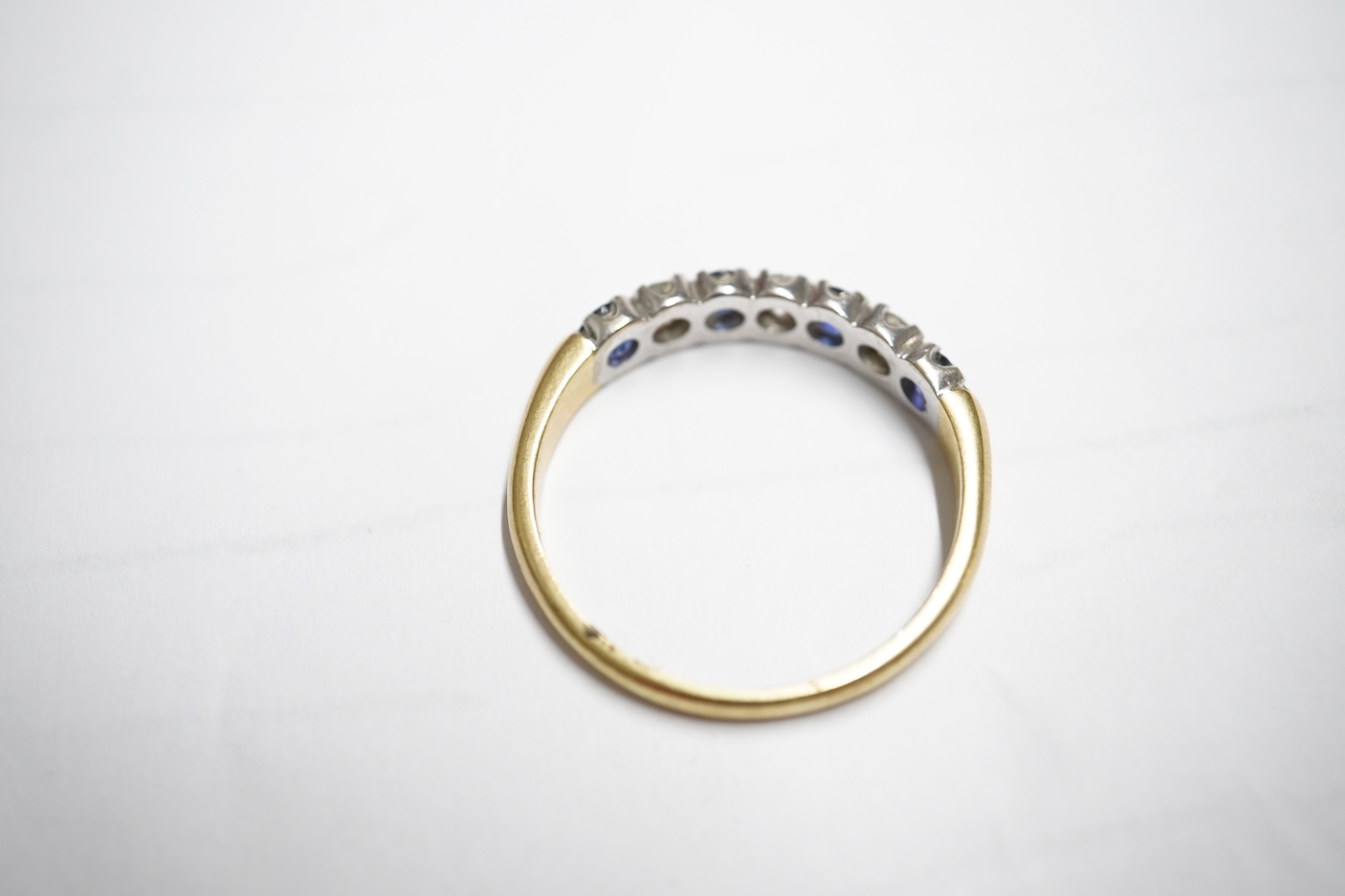A sapphire and diamond ring, set with an alternating sequence of brilliant-cut diamonds totalling approximately 0.45 carats, and circular-cut sapphires, in 18ct gold, size Z+, British hallmarks, gross weight approximatel